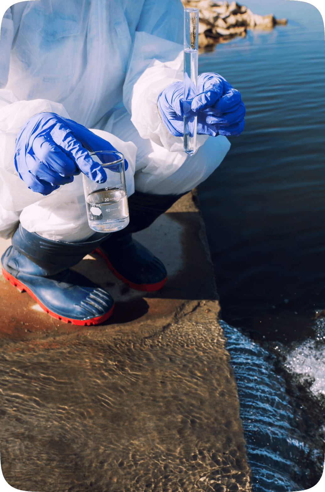 Field researcher in protective gear collecting a water sample from a river