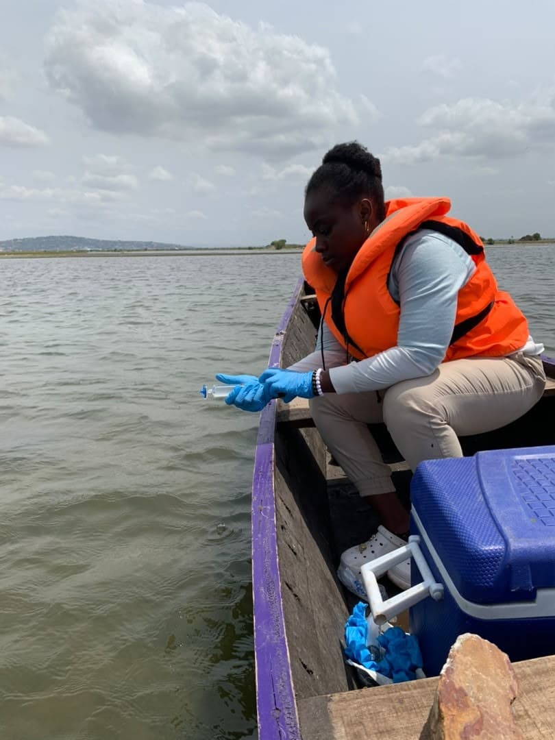 Researcher in a life jacket on a boat collecting a water sample